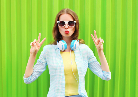 Pretty cool woman listens to music in headphones over green backgroundの写真素材