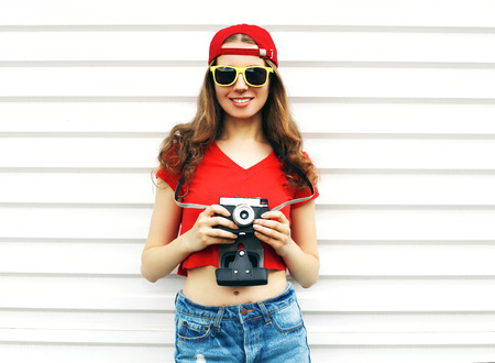 Fashion pretty smiling woman holding retro camera over white backgroundの写真素材