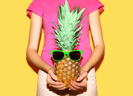 Fashion pineapple with sunglasses on hands woman over yellow backgroundの写真素材