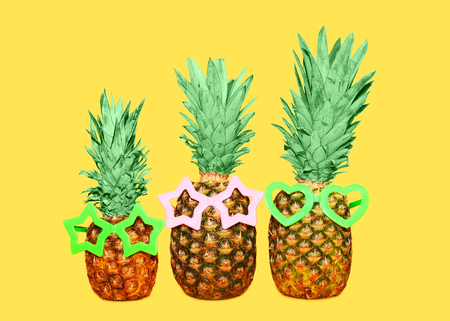 Three pineapple and sunglasses on yellow background, colorful ananas photoの写真素材