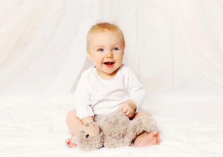 Happy smiling baby playing with on bed at home
