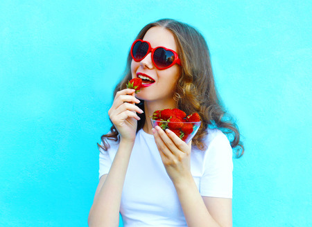 Pretty woman with many strawberry over colorful blue backgroundの写真素材