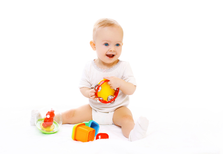 Happy smiling baby playing with toys on white backgroundの写真素材