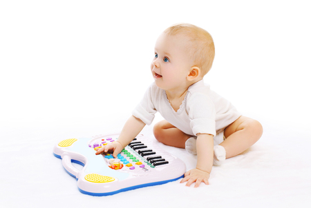 Cute baby playing with toy piano on a white backgroundの写真素材