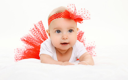 Portrait cute little baby girl lying in red skirt on bedの写真素材