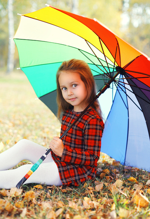 Portrait beautiful little girl child with colorful umbrella in autumn dayの写真素材