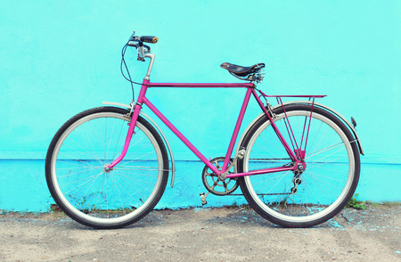 Retro pink bicycle stands over colorful blue backgroundの写真素材