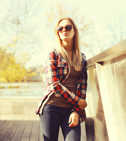 Fashion pretty woman wearing a sunglasses and checkered shirt in the cityの写真素材