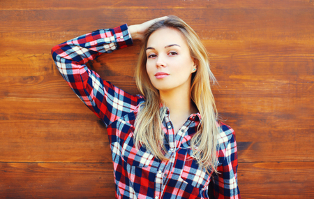 Fashion pretty woman wearing a sunglasses and checkered shirt over wooden backgroundの写真素材