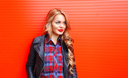 Fashion portrait pretty blonde woman wearing black rock style over colorful red background