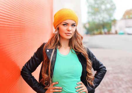 Fashion pretty young woman wearing jacket hat over colorful red background