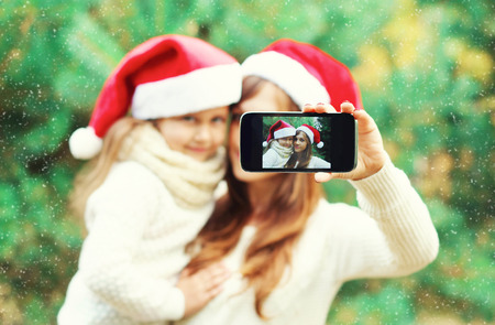 Christmas mother and child taking picture self portrait on smartphone together, closeup, blurred...