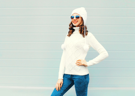 Happy young smiling woman wearing a knitted hat, sweater over background