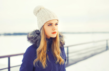 Fashion winter portrait blonde woman wearing a jacket and knitted hat outdoors