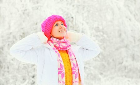 Fashion winter portrait happy woman wearing colorful knitted hat sweater scarf over snowy backgroundの写真素材