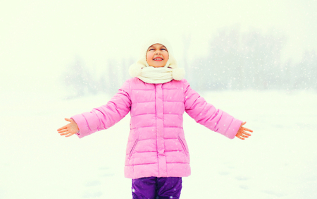 Winter happy smiling little girl child enjoys snowflakes in snowy dayの写真素材