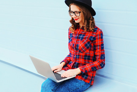 Fashion young smiling woman working using laptop computer outdoors in cityの写真素材