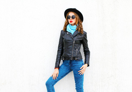 Fashion pretty woman posing wearing black rock jacket, hat over white background