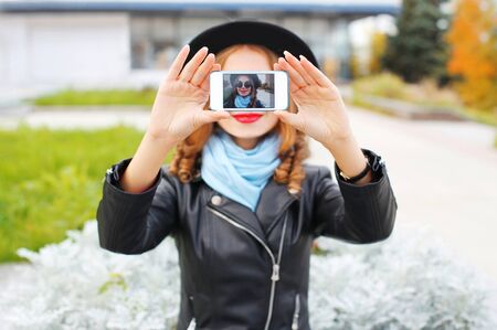 Fashion woman taking photo self portrait on smartphone in city closeup screen