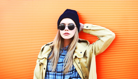 Fashion portrait pretty blonde woman in black sunglasses and hat on a colorful orange background closeupの写真素材