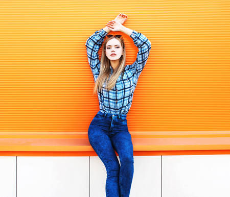 Fashion beautiful blonde slim woman posing on a colorful orange backgroundの写真素材
