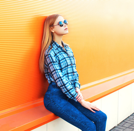 Fashion beautiful blonde woman posing on a colorful orange backgroundの写真素材