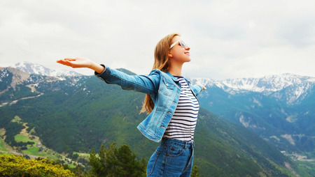 Happy travel woman enjoys fresh air mountains raises hands up over view landscape Spain background