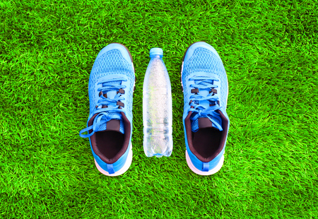 blue sports sneakers and plastic bottle of water on the green grass textured background, empty copy spaceの写真素材