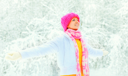 Happy smiling woman in colorful knitted hat, scarf enjoys on snowy backgroundの写真素材