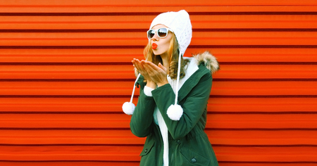 Fashion pretty woman blowing red lips sends an air kiss on backgroundの写真素材