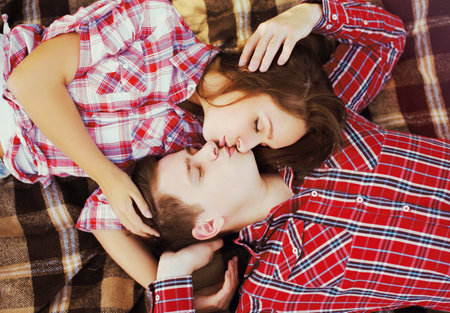 Portrait of young couple teenagers kissing lying together on a plaid, top viewの写真素材