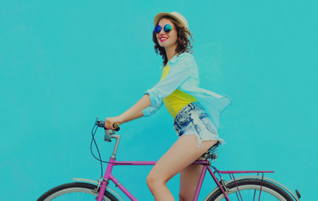 Happy young smiling woman with bicycle on a blue backgroundの写真素材