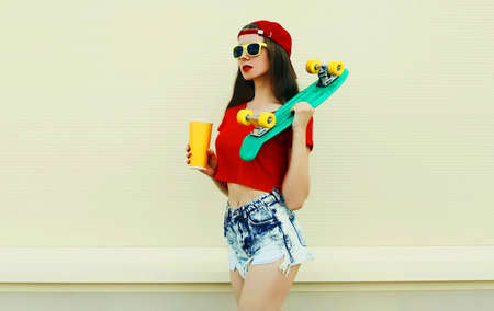 Young woman with green skateboard wearing a shorts and red baseball cap in a cityの写真素材