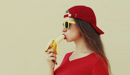 Portrait of woman eating banana on a white backgroundの写真素材
