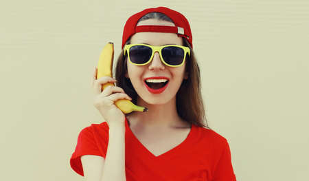 Portrait of funny woman calling on a banana phone on a white backgroundの写真素材