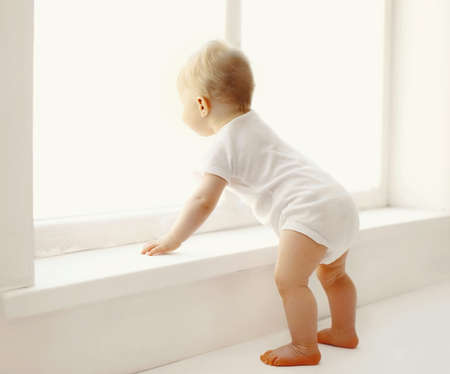 little baby touching window in white room at homeの写真素材