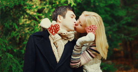 Winter portrait of happy young kissing couple in love outdoors on christmas tree background