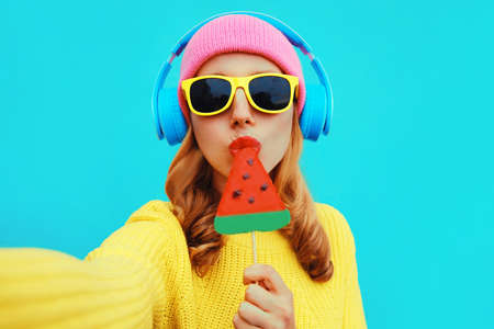 Summer fresh colorful portrait of young woman taking selfie in headphones listening to music with...