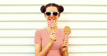 Summer portrait of happy smiling young woman with lollipop on white backgroundの写真素材