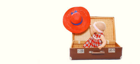 Child sitting in suitcase with red summer straw hat on white backgroundの写真素材