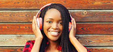Portrait of happy smiling african woman listening to music in headphones in the cityの写真素材