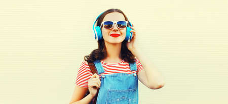Portrait of happy smiling young woman with headphones listening to music on white background