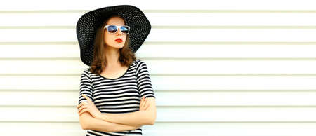 Portrait of beautiful woman model wearing black round summer hat, striped dress on white backgroundの写真素材