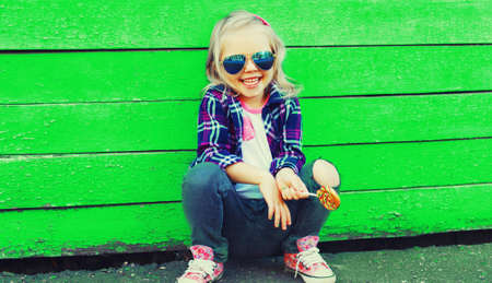 Portrait of stylish little girl child model posing on vivid green background