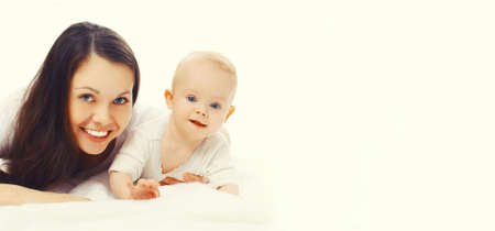 Portrait of happy smiling mother and baby lying on the floor together on white background, blank copy space for advertising textの写真素材