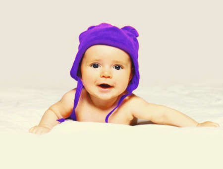 Portrait of happy smiling baby in hat lying on the bed on white backgroundの写真素材