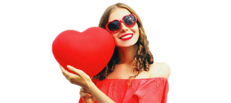 Portrait of happy smiling woman with red heart shaped balloon wearing sunglasses isolated on white backgroundの写真素材