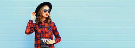 Portrait of happy smiling young woman photographer with film camera on blue background, blank copy space for advertising textの写真素材
