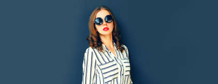 Portrait of beautiful young woman wearing white striped shirt on dark backgroundの写真素材