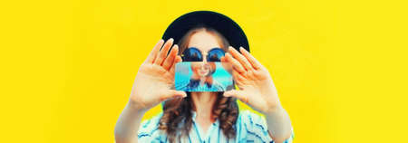 Close up of modern young woman stretching her hands taking selfie with smartphone on yellow backgroundの写真素材